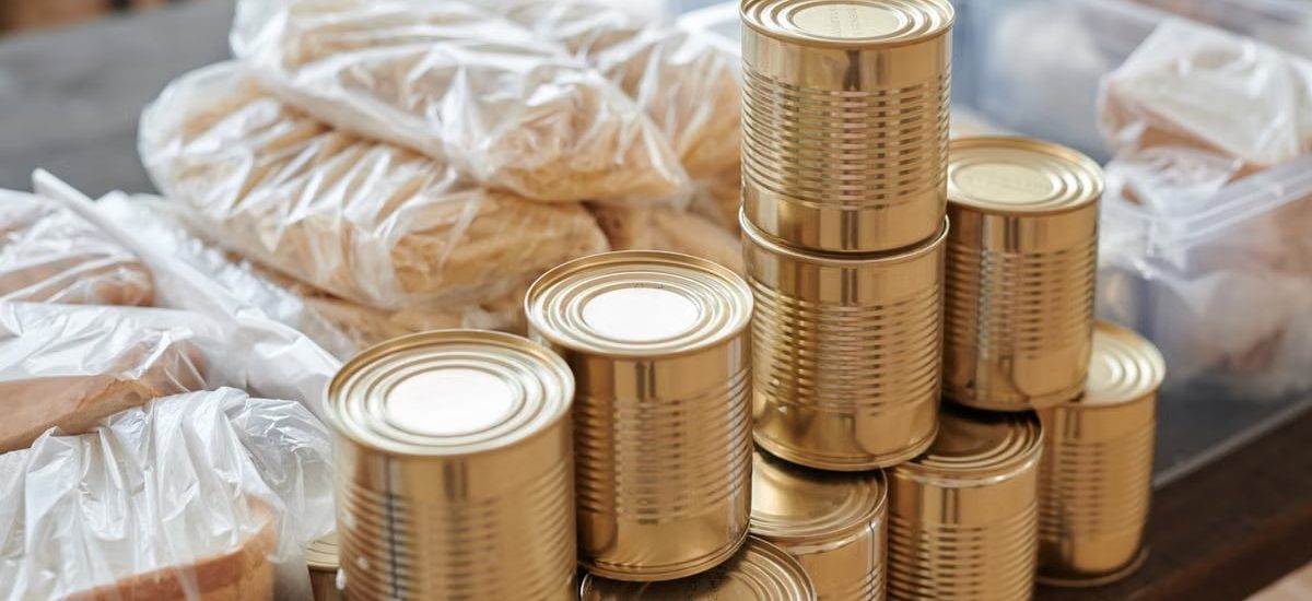 A stack of canned goods and packaged foods on a table, perfect for donation drives.