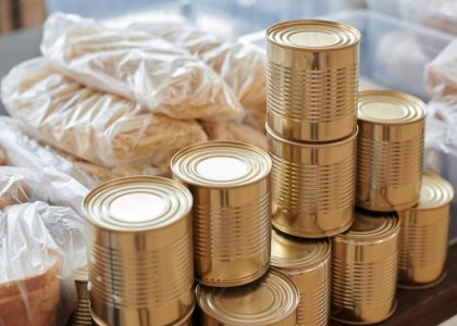 A stack of canned goods and packaged foods on a table, perfect for donation drives.